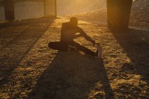 Homme afro-américain faisant de l'exercice à l'extérieur, s'étirant sous le pont au coucher du soleil. mode de vie sain en plein air entraînement fitness. — Photo de stock