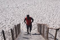 Homme afro-américain faisant de l'exercice, montant les escaliers par une journée ensoleillée. mode de vie sain en plein air entraînement fitness. — Photo de stock