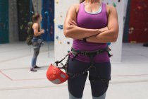 Milieu de la femme caucasienne avec casque se préparant à l'escalade au mur d'escalade intérieur. fitness et temps libre au gymnase. — Photo de stock