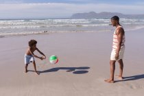 Afrikanisch-amerikanischer Vater und Sohn amüsieren sich am Strand mit Ball. Familienfreizeit im Freien am Meer. — Stockfoto