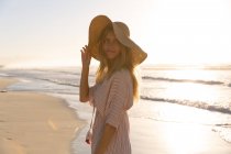 Белая женщина в пляжном покрывале и шляпе, развлекающаяся на пляже. здоровый отдых на открытом воздухе у моря. — стоковое фото