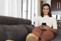 Feliz mestiço transgênero mulher relaxante na sala de estar sentado no sofá tomando selfies. ficar em casa em isolamento durante o confinamento de quarentena. — Fotografia de Stock