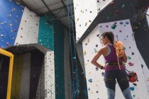 Кавказька жінка з мотузкою на плечі готується до сходження на стіну в приміщенні. Фізкультура та вільний час у спортзалі. — стокове фото