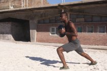Африканский американец, тренирующийся с гирями на пляже в солнечный день. фитнес-тренировки. — стоковое фото