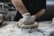 Der mittlere Teil des professionellen Kochs bereitet Teig mit Hygienehandschuhen vor. Arbeit in einer belebten Restaurantküche. — Stockfoto