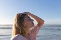 Caucasian woman wearing beach cover up touching her hair at the beach. healthy outdoor leisure time by the sea. — Stock Photo