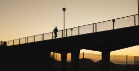 African american man exercising outdoors running on bridge at sunset. healthy outdoor lifestyle fitness training. — Stock Photo