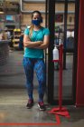 Porträt einer kaukasischen Frau mit Maske, die auf dem Flur eines Fitnessstudios steht. Fitness und Freizeit im Fitnessstudio während der Coronavirus-Pandemie 19. — Stockfoto