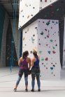 Due donne caucasiche felici che parlano e si preparano per una scalata sulla parete interna. fitness e tempo libero in palestra. — Foto stock