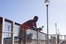 Африканский американец тренируется, отдыхает, держит бутылку в солнечный день. фитнес-тренировки. — стоковое фото