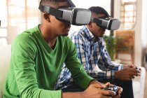 Afrikanische amerikanische Brüder tragen vr Headset und spielen Videospiele, während sie zu Hause auf der Couch sitzen. Spiel- und Unterhaltungstechnikkonzept — Stockfoto