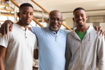 Портрет афроамериканського старшого чоловіка та його двох синів, які посміхаються, стоячи вдома. батьківство та концепція сім'ї — стокове фото