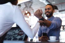 Lächelnder männlicher Kunde mit gemischter Rasse, der mit einer Smartwatch bei einer afrikanisch-amerikanischen Barista bezahlt. unabhängiges Café, erfolgreiches Kleinunternehmen. — Stockfoto