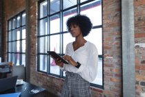 Afroamerikanerin steht, benutzt Tablet und arbeitet im Café. Digitale Kreative unterwegs. — Stockfoto