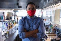 Porträt eines männlichen Baristas gemischter Rasse mit Gesichtsmaske. Unabhängiges Café, Geschäfte während der Coronavirus-Pandemie 19. — Stockfoto