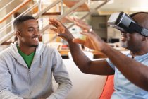 African american young man teaching his father how to use vr headset at home. family and entertainment technology concept — Stock Photo