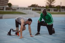Atleta maschio caucasico con gamba protesica in posizione di partenza per correre in pista. concetto di sport paralimpico — Foto stock
