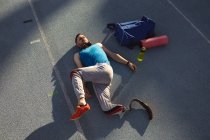 Atleta maschio caucasico con gamba protesica che fa esercizio di stretching su pista da corsa. concetto di sport paralimpico — Foto stock