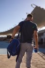 Vista trasera de atleta masculino caucásico con pierna protésica de pie en el campo de deportes. concepto de deporte paralímpico - foto de stock