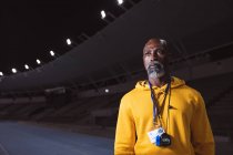 Африканский старший тренер-мужчина стоит на беговой дорожке ночью. Концепция паралимпийских игр — стоковое фото