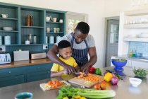 Pai e filho afro-americanos na cozinha, a cozinhar juntos. em casa em isolamento durante o confinamento de quarentena. — Fotografia de Stock