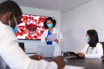 Médecine afro-américaine portant un masque facial donnant une présentation à une équipe de médecins. soins de santé et recherche médicale pendant la pandémie de covide 19 — Photo de stock