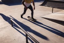 Baixa seção de homem caucasiano skate ao sol. sair em um parque de skate urbano no verão. — Fotografia de Stock