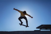 Uomo caucasico che salta e fa skateboard nelle giornate di sole. appendere fuori a skatepark urbano in estate. — Foto stock
