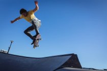 Homem branco a saltar e a andar de skate num dia ensolarado. sair no parque de skate urbano no verão. — Fotografia de Stock