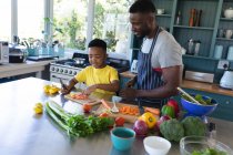 African american father and son in kitchen, cooking together. at home in isolation during quarantine lockdown. — Stock Photo
