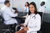 Portrait of african american female doctor smiling while sitting on a chair in meeting room. healthcare and professionalism concept — Stock Photo