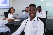 Ritratto di un medico afro-americano sorridente seduto su una sedia in sala riunioni. concetto di assistenza sanitaria e professionalità — Foto stock