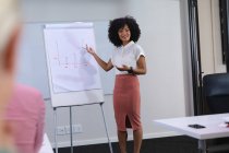 Donna afroamericana che fa una presentazione ai suoi colleghi d'ufficio nella sala riunioni dell'ufficio. business, professionalità, ufficio e concetto di lavoro di squadra — Foto stock
