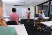 Mujer afroamericana dando una presentación a sus colegas de oficina en la sala de reuniones en la oficina. negocio, profesionalidad, concepto de oficina y trabajo en equipo - foto de stock