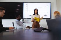 Indian woman giving a presentation to her office colleagues in meeting room at office. business, professionalism, office and teamwork concept — Stock Photo