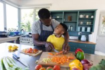 Afro-americanos pai e filho na cozinha, cozinhar juntos em casa em isolamento durante o bloqueio de quarentena. — Fotografia de Stock