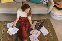 Caucasian woman working at home sitting on floor with paperwork and laptop. working at home in isolation during quarantine lockdown. — Stock Photo