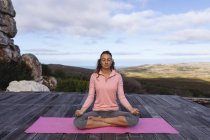 Mulher caucasiana feliz praticando ioga sentado em meditação no cenário de montanha rural. vida saudável, fora da grade e perto da natureza. — Fotografia de Stock