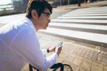 Mittelteil eines asiatischen Geschäftsmannes mit Smartphone, das mit Fahrrad in der Stadtstraße steht. Digitaler Nomade im Stadtkonzept unterwegs. — Stockfoto