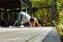 Madre asiatica e sua figlia praticano yoga in terrazza in giardino. a casa isolata durante l'isolamento in quarantena. — Foto stock