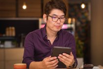 Азиатский бизнесмен, использующий планшеты и беспроводные наушники в кафе. деловые поездки, цифровая реклама на ходу и о концепции города. — стоковое фото