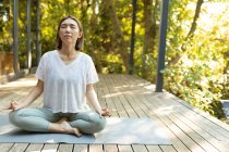 Donna asiatica che pratica yoga con gli occhi chiusi sulla terrazza in giardino. a casa isolata durante l'isolamento in quarantena. — Foto stock