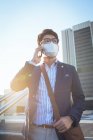 Uomo d'affari asiatico che indossa maschera facciale utilizzando smartphone in strada della città. nomade digitale in giro per la città durante il concetto pandemico covid 19. — Foto stock