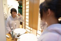 Азиатка в очках чистит зубы в ванной. в доме в изоляции во время карантинной изоляции. — стоковое фото