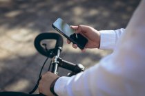 Розрив бізнесмена за допомогою смартфона, що стоїть з велосипедом на міській вулиці. цифровий кочівник і близько в міській концепції . — стокове фото
