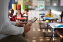 Der mittlere Teil der männlichen Lehrer nutzt ein digitales Tablet, während sie in der Klasse der Grundschule sitzen. Schul- und Bildungskonzept — Stockfoto