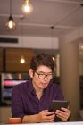Asian businessman using tablet and wireless earphones in cafe. business travel, digital nomad on the go out and about in city concept. — Stock Photo