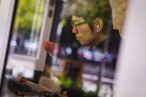 Азіатський бізнесмен за допомогою ноутбука і бездротових навушників п'є каву в кафе. Подорожі бізнесу, цифровий кочівник в дорозі і про про про про в міській концепції. — стокове фото