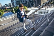 Asian businessman talking on smartphone walking up steps in city street. digital nomad out and about in city concept. — Stock Photo