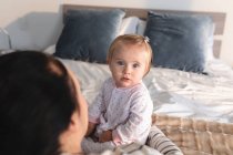 Porträt eines kaukasischen Babys, das zu Hause auf dem Bett sitzt. Mutterschaft, Liebe und Babypflege-Konzept — Stockfoto